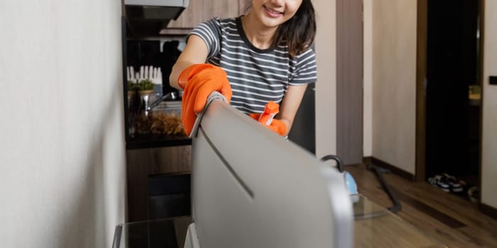 Woman maid cleaning and wiping the computer with microfiber cloth in office.