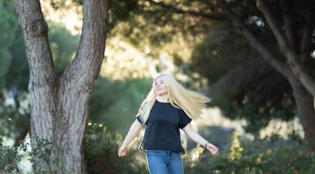 A young woman with braces is walking down a street lined with trees in the background.