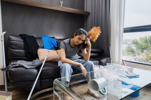 Shocked woman with messing home while cleaning house. Young girl surrounded by many of clothes and trash.