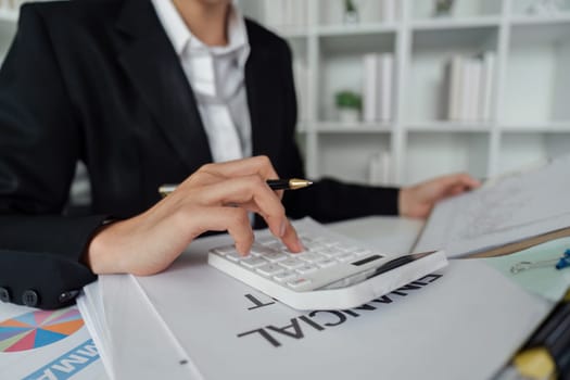 Businesswoman using a calculator to calculate numbers on a company's financial documents, she is analyzing historical financial data to plan how to grow the company. Financial concept.