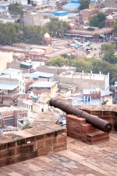 Ancient iron cannon set on the walls of a fort looking out over the city of jodhpur, jaipur, udaipur showing the defences of the ancient Rajput kings