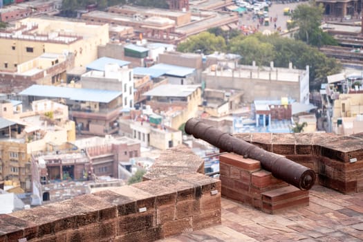 Ancient iron cannon set on the walls of a fort looking out over the city of jodhpur, jaipur, udaipur showing the defences of the ancient Rajput kings