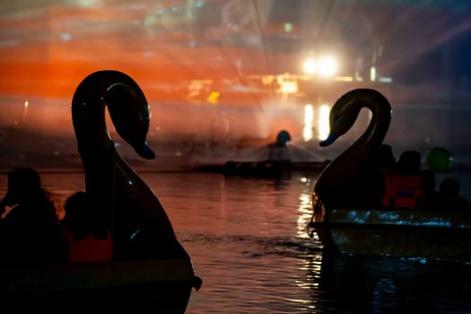 People in a swan shaped boat enjoying the light, sound and fountains show at Gadisar lake showing the famous tourist spot near Jodhpur and a place to relax in India