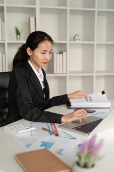 Young business woman asian or employee accounting bookkeeping documents checking financial data or marketing report working in office with laptop. Paperwork management.