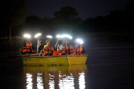 Jaisalmer, Rajasthan, India - 28th Dec 2023: People sitting in a boat on a dark lake flashing lights from their phones and enjoying the music relaxing, waiting for rescue, celebrating on Gadisar lake Jaisalmer Jodhpur
