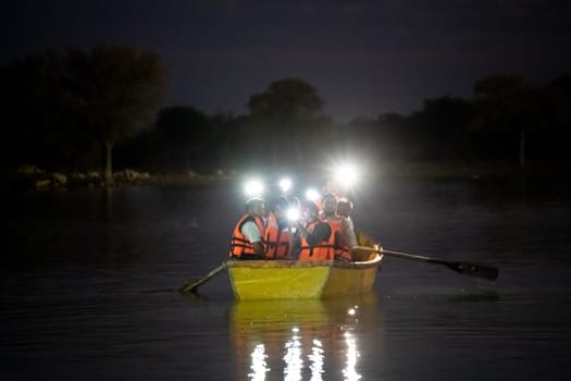 Jaisalmer, Rajasthan, India - 28th Dec 2023: People sitting in a boat on a dark lake flashing lights from their phones and enjoying the music relaxing, waiting for rescue, celebrating on Gadisar lake Jaisalmer Jodhpur