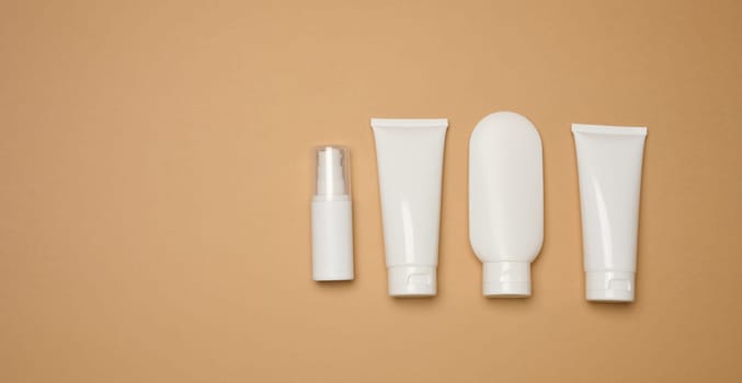 White plastic tubes, jars, and containers for cosmetic products on a brown background, advertising and branding of products