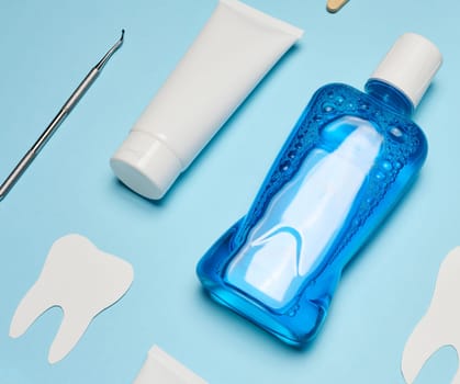 Mouthwash, toothpaste tube, dental floss on a blue background, oral hygiene. Top view