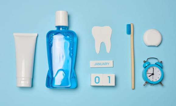 Mouthwash, toothpaste tube, dental floss on a blue background, oral hygiene. Top view