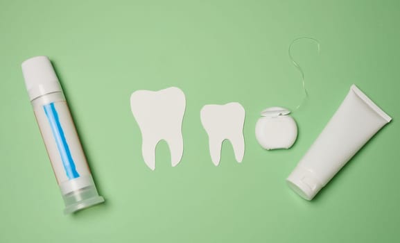 Toothpaste and dental floss on a green background, top view. Oral hygiene