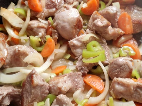 fried pork with onions and carrots close-up for food background