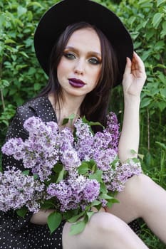 A fashionable girl with dark hair, a spring portrait in lilac tones in summer. Bright professional makeup