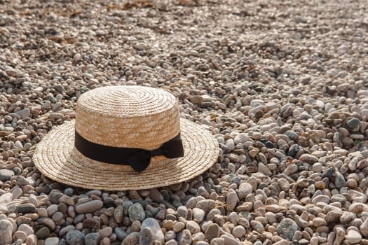 A straw hat on the beach. Pebbles on the seashore, close-up. The natural background.