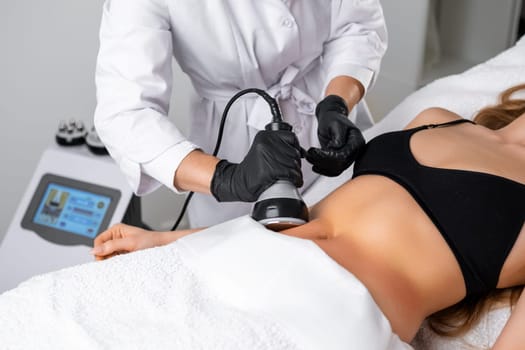 Engaging in ultrasound cavitation therapy for body contouring and anti cellulite treatment, a young woman benefits from hardware cosmetology techniques aimed at sculpting her body.