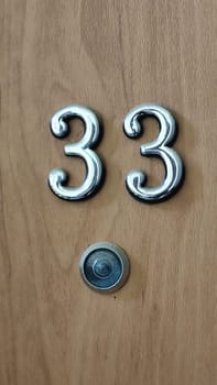numbers 33 on a white exterior apartment door, symbol objects, sky. High quality photo
