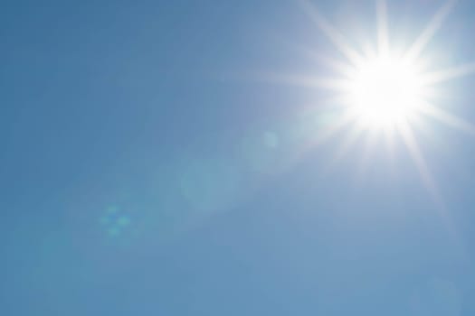 Sharp sunbeams on a cloudless day in summer and holiday time. Clear blue sky background.