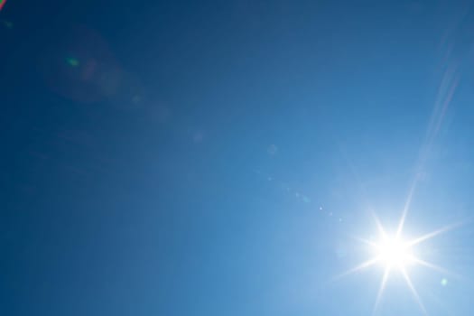 Sharp sunbeams on a cloudless day in summer and holiday time. Clear blue sky background.