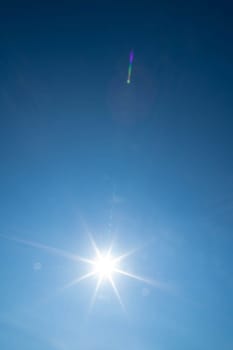 Sharp sunbeams on a cloudless day in summer and holiday time. Clear blue sky background.