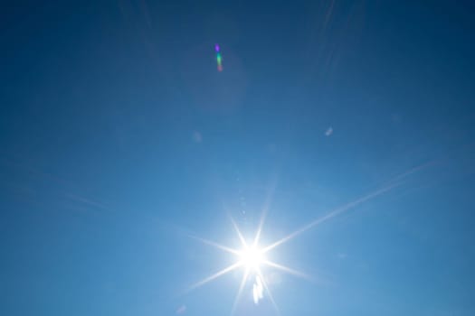 Sharp sunbeams on a cloudless day in summer and holiday time. Clear blue sky background.