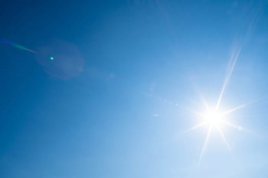 Sharp sunbeams on a cloudless day in summer and holiday time. Clear blue sky background.