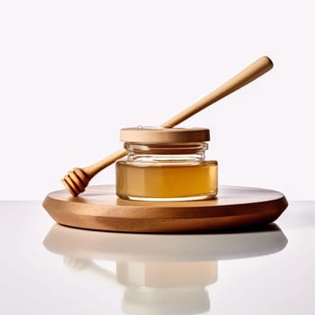 A wooden spoon is next to a jar of honey. The spoon is made of wood and has a curved handle. The jar of honey is in a glass container and is sitting on a white background