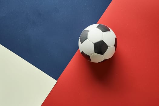 A soccer ball placed on top of a red, white, and blue colored floor, showcasing the classic sports equipment against a patriotic backdrop.