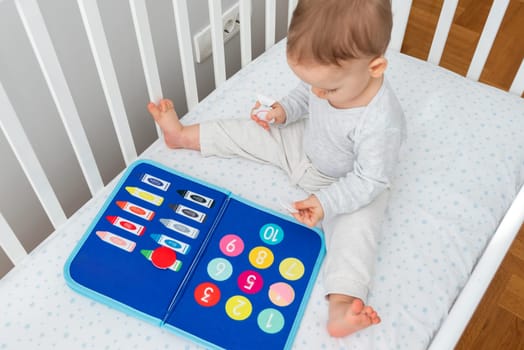Joy of early childhood learning with a baby interacting with a Montessori busy book in a crib, perfectly blending the concepts of smart books and modern educational toys for early development