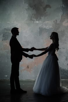 Cute wedding couple in the interior of a classic studio. They kiss and hug each other.