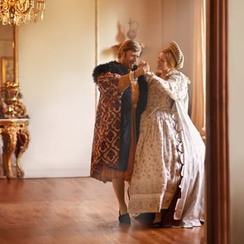 Renaissance, man and woman dance in castle together with vintage love, romance and banquet performance. Medieval king, queen or royal couple in ballroom holding hands with smile in palace in Europe.