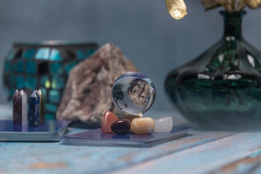 A serene tarot card reading space with assorted healing crystals, a candle lantern, and a geode on a weathered wooden surface