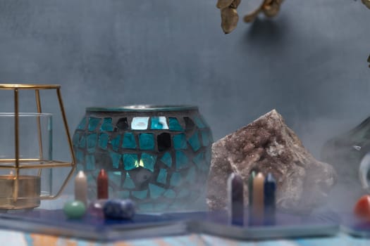 A serene tarot card reading space with assorted healing crystals, a candle lantern, and a geode on a weathered wooden surface