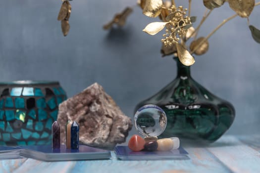 A serene tarot card reading space with assorted healing crystals, a candle lantern, and a geode on a weathered wooden surface