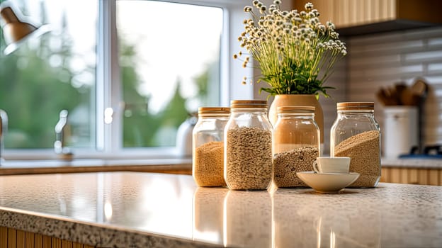 A kitchen counter with four glass jars of different sizes and a white cup. The jars are filled with various grains and the cup is empty. Concept of organization and order