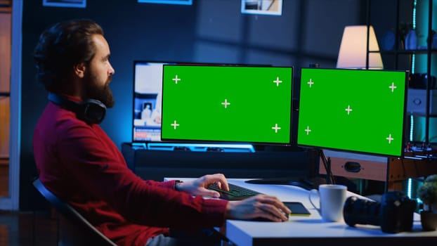 Photo editor using green screen monitor to color correct photographs in creative studio. Photographer selecting best pictures for editorial content with chroma key desktop computer