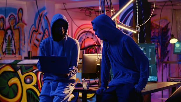 New member in hacking group receiving guidance from experienced rogue programmer acting as his mentor in underground hideout. Master hacker teaches script kiddie how to develop malware