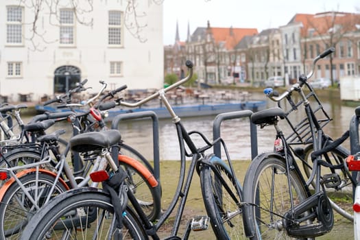 Bicycles parked alongside a channel on beautiful old buildings background.