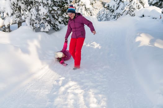 A mother and daughter as they dash along a serene snowy path, embracing the tranquil beauty of their winter mountain getaway.