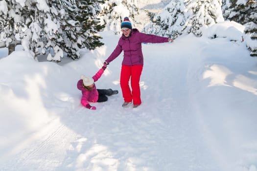 A mother and daughter as they dash along a serene snowy path, embracing the tranquil beauty of their winter mountain getaway.