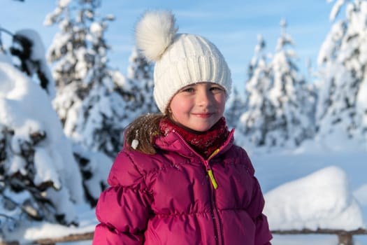 A radiant girl smiles against a backdrop of snow-capped mountains, the sun illuminating her joyful expression.