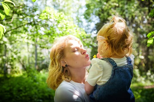 A mother and young daughter sharing a loving gaze among vibrant green trees