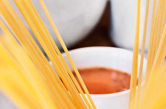 Uncooked  pasta spaghetti and tomato sauce ,  preparing traditional italian food