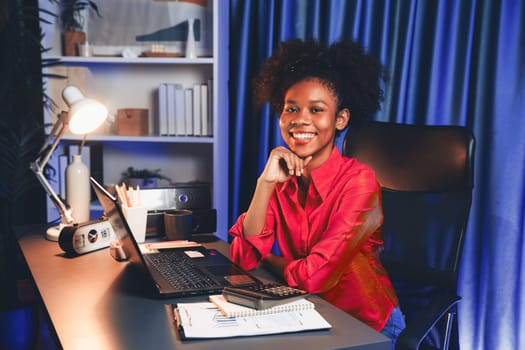 African woman blogger wearing pink shirt with happy face, looking on screen laptop with valued achievement project or get scholarship. Concept of cheerful expression work from home. Tastemaker.