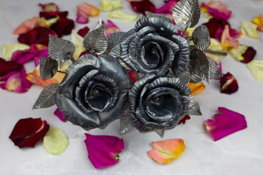 Bouquet of metal roses for the holiday on background of rose petals