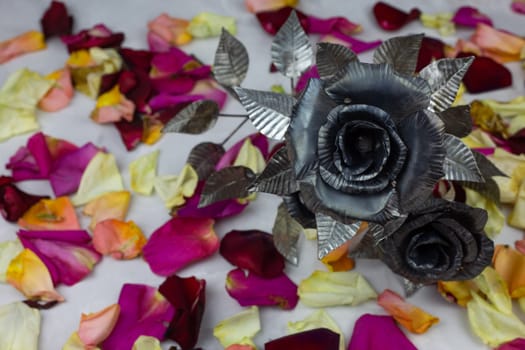 Rough metal roses next to delicate petals of fresh flowers