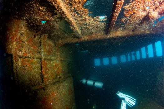 scuba divers exploring a shipwreck underwater