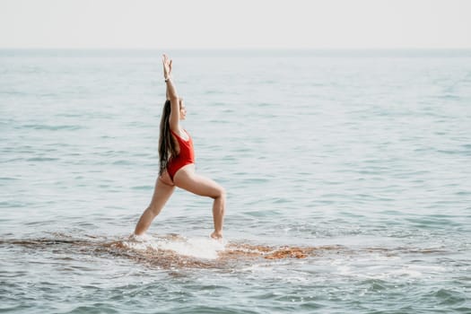 Woman sea yoga. Back view of free calm happy satisfied woman with long hair standing on top rock with yoga position against of sky by the sea. Healthy lifestyle outdoors in nature, fitness concept.