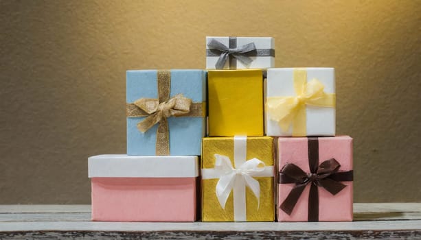 A stack of boxes with gold ribbons on them. Gold background with colorful present boxes different size for anniversary, wedding, birthday