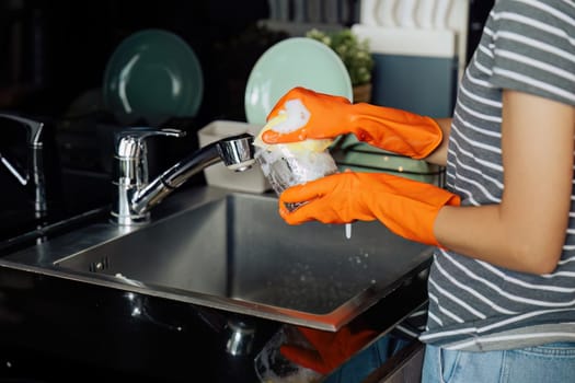 housewife cleans the house and washes the dishes at the sink. Cleaning home concept.