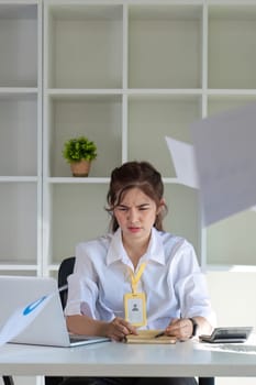 Asian businesswoman who is tired and has a headache from difficult work causing stress Sitting and looking at work at the desk in the office..