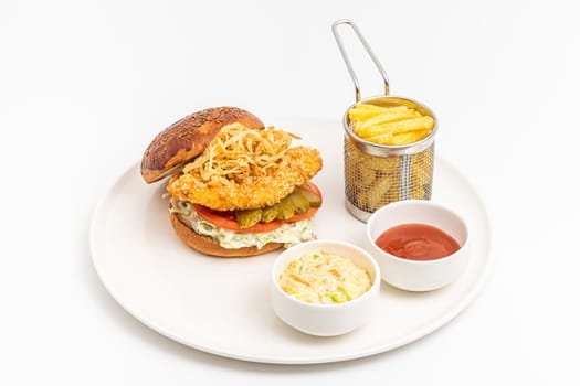 Chicken burger served with fries and sauces on a white porcelain plate